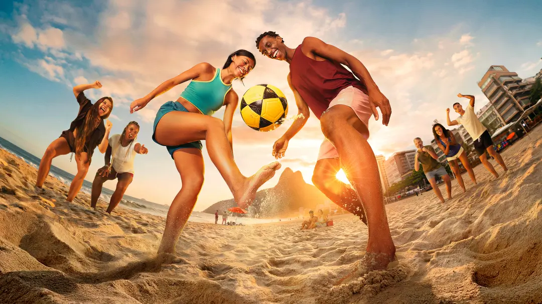Young Brazilians playing football on the beach at sunset